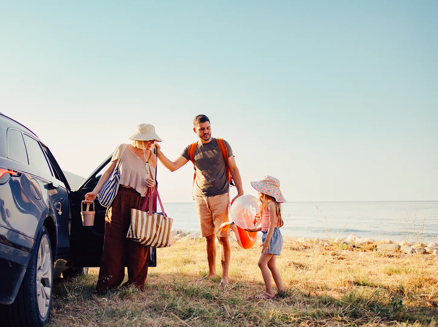 family by the car at the beach